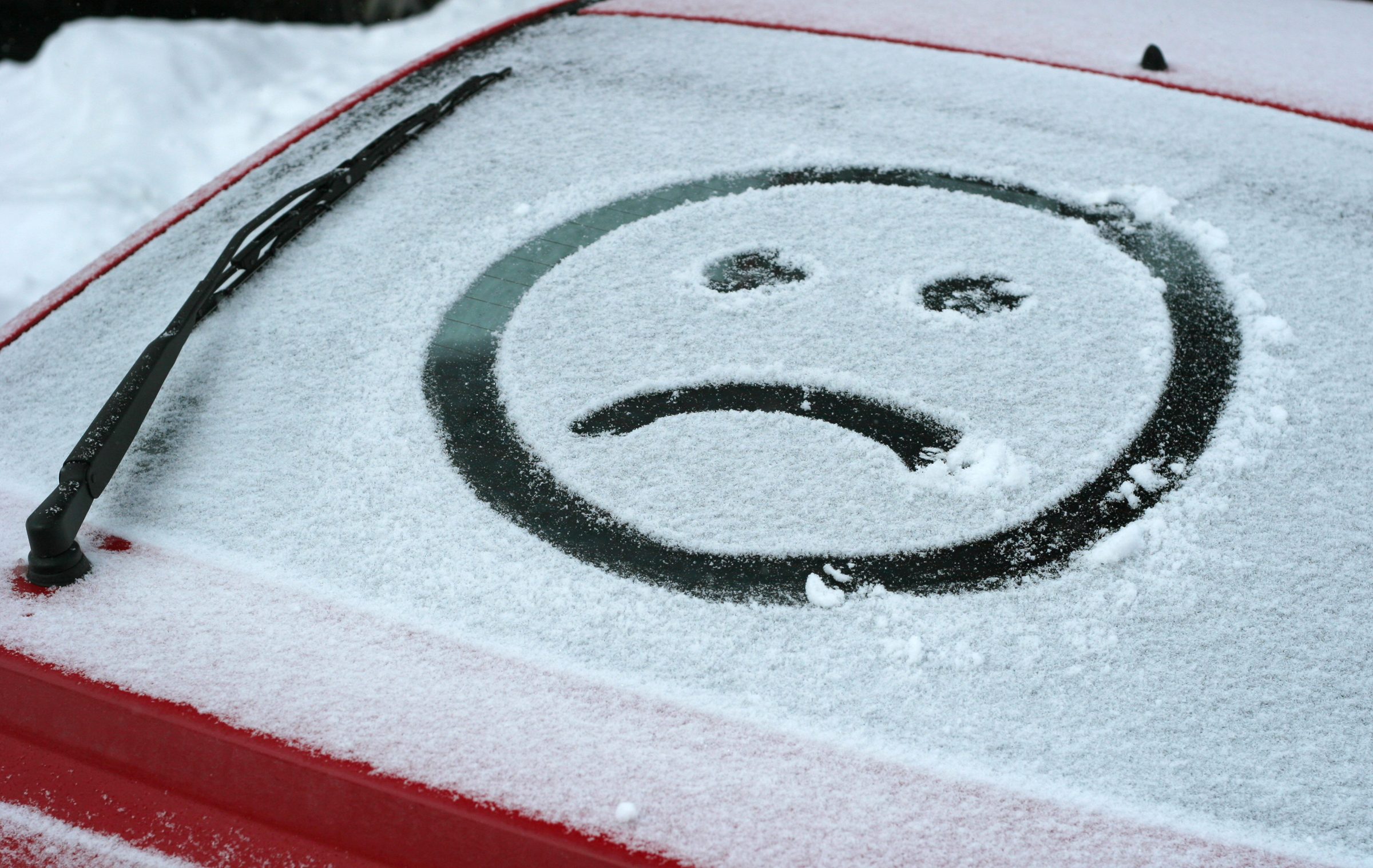 Sad face in snow on car.