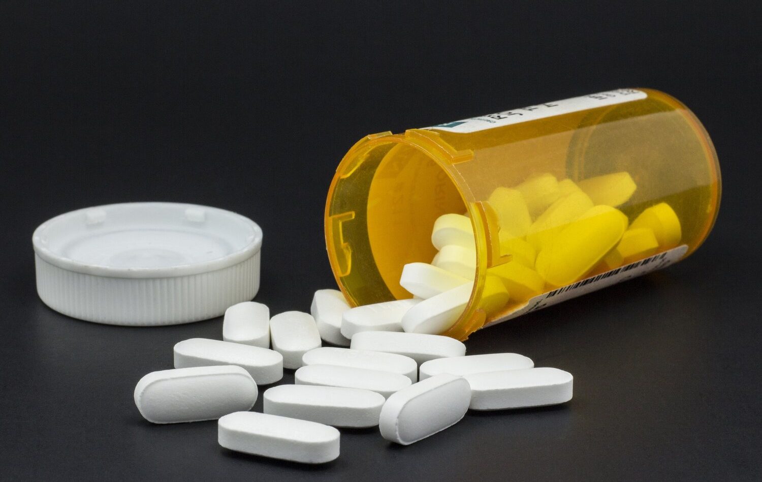 Bottle of spilled pills on black background